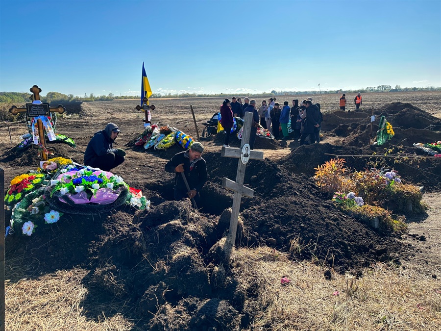 Сім’я навідує могили вранці після похорону. У цей час копачі роблять кілька нових могил